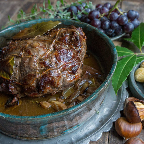 Wildschweinbraten aus der Keule in einem Bräter mit herbstlicher Dekoration